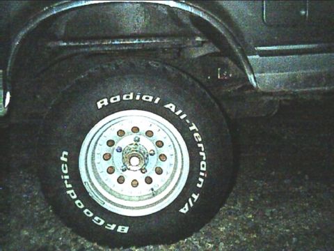 1989 Ford Bronco - Close-up of a rear wheel and tire on a truck, showing a BFGoodrich Radial All-Terrain T/A with raised white lettering on a chrome five-slot…