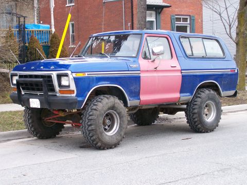 1979 Ford Bronco - This lifted Ford Bronco has a blue body with a contrasting pink driver's side door and large off-road tires.