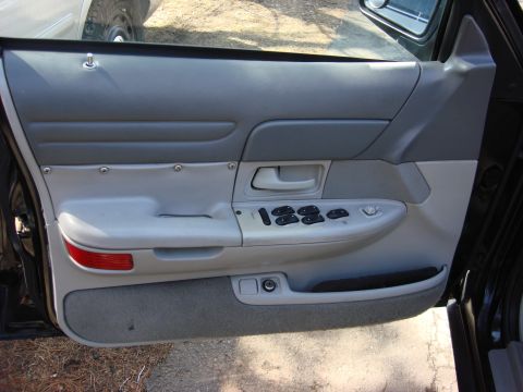 2003 Ford Crown Victoria - The interior door panel of a 2003 Ford Crown Victoria features gray trim and power window controls.
