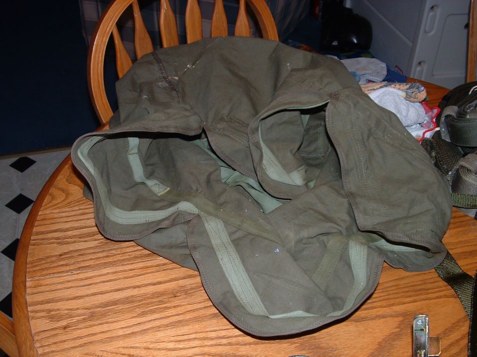Olive-drab military canvas bag or cover on a wooden kitchen table