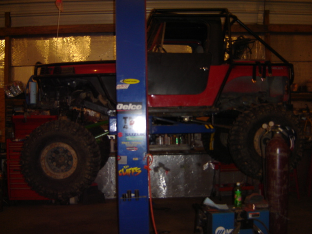 Red and black off-road vehicle on a lift, side view