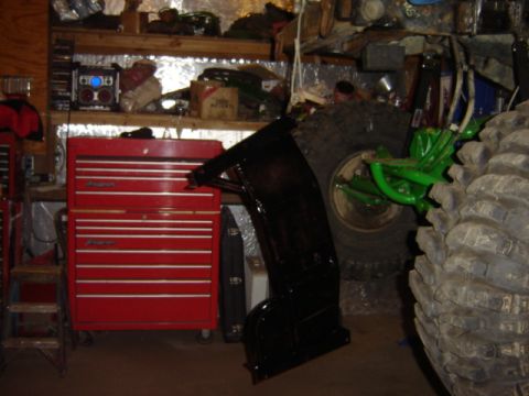 1992 Ford Bronco - A black vehicle part is shown in a garage next to a red toolbox and large tires.