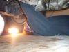 1987 Ford Bronco - Close-up view of the underside of a vehicle, partially obscured by a blue tarp.