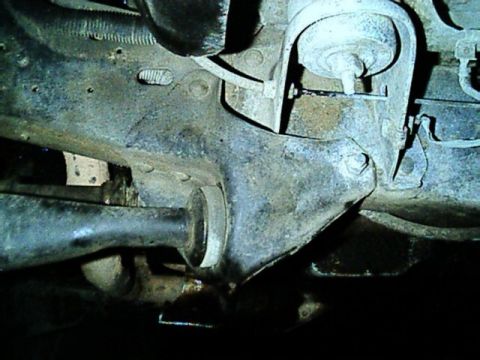 1989 Ford Bronco - View from beneath the truck of the rear radius-arm mount where the arm passes through its bushing into a bracket on the frame crossmember,…
