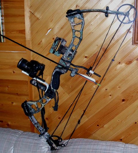 1988 Ford Bronco - A compound bow with a camera attached is displayed against a wood-paneled wall.