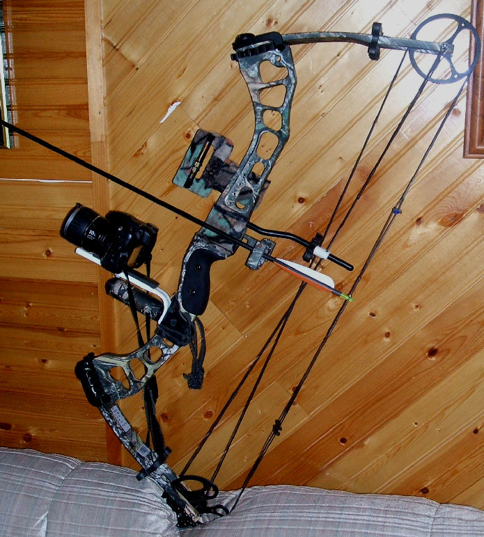 Compound bow with camouflage pattern, mounted camera, and arrow