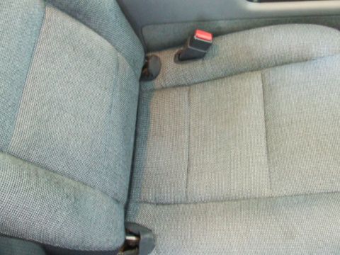 2003 Ford Crown Victoria - The fabric upholstery on the car's seats is visible, along with a seatbelt buckle.