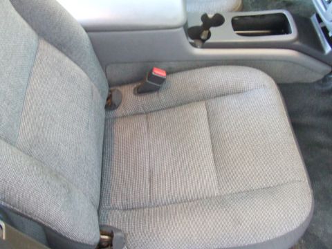2003 Ford Crown Victoria - Close-up view of the fabric seat and center console area of a vehicle.