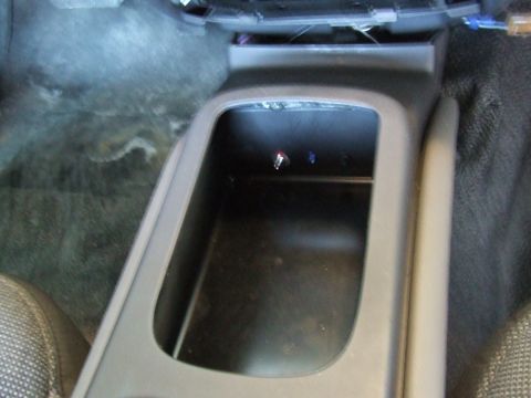 2003 Ford Crown Victoria - The interior of a car shows a center console with an open storage compartment and some exposed wires.