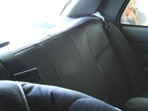 2003 Ford Crown Victoria - The rear seat of a car, showing the black upholstery and a seatbelt mechanism.