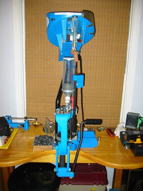 1996 Ford Bronco - A blue reloading press is set up on a wooden table, surrounded by various reloading components and tools.