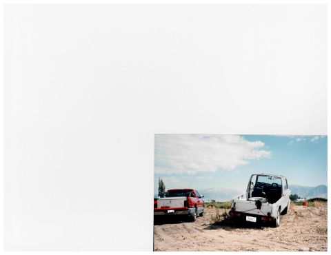 1988 Suzuki Samurai - Two pickup trucks are parked in a dry, dusty landscape under a cloudy blue sky.