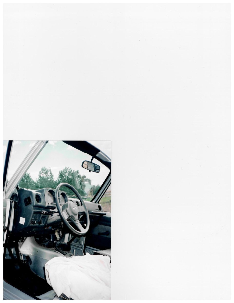 Scanned photo of stripped Suzuki Samurai interior: gray dash, steering wheel, floor shifters, roll bar