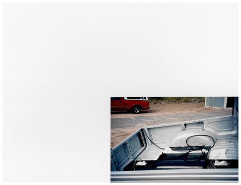 1988 Suzuki Samurai - A red pickup truck with a white camper shell is parked on a gravel lot, seen from the perspective of another vehicle's bed.