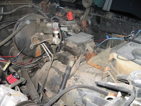 1994 Ford Bronco - This image shows various engine bay components, including the brake master cylinder and fuse box, with visible wiring and some rust.