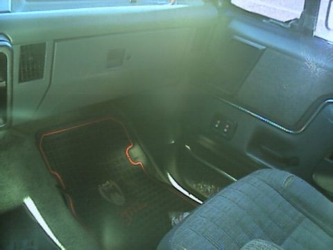 1989 Ford Bronco - Passenger-side interior view of a truck cab showing the glovebox door, dash vents, door panel with power window switches, and a red-trimmed…