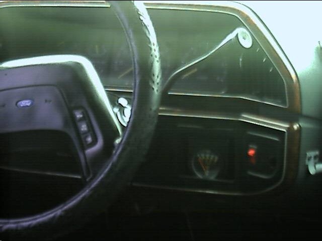 Aftermarket gauge and red switch mounted in dash bezel beside Ford steering wheel