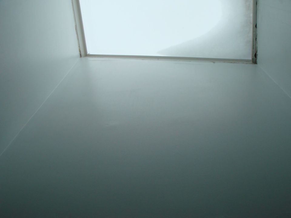 Interior view looking up at a skylight with white ceiling panels