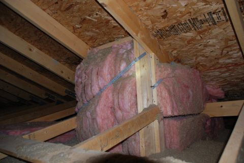 1996 Ford Bronco - Attic space shows exposed wooden beams and pink fiberglass insulation packed into the rafters.