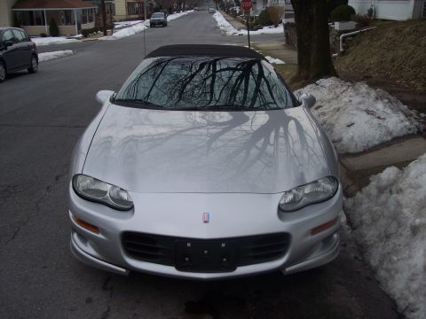 2000 Chevrolet Camaro - A silver convertible sports car is parked on a street with snow piles on the side.