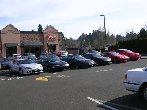 2007 Mazda 3 - Multiple Mitsubishi Eclipse models are parked in a lot outside a commercial building.