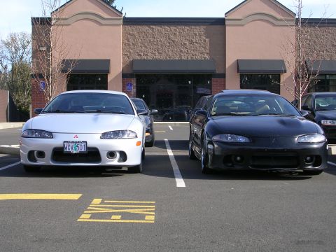 2007 Mazda 3 - Two Mitsubishi Eclipse models are parked side-by-side in a parking lot, with the front of both vehicles visible.