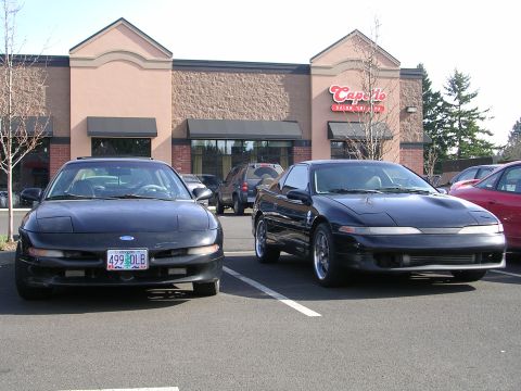 2007 Mazda 3 - Two coupes are parked in a lot in front of a building with a sign that says Capello's.