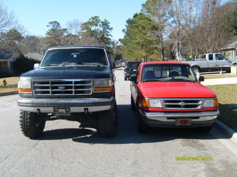 1992 Ford Bronco - Two Ford trucks, a large F-Series and a smaller Ranger, are parked on a residential street.