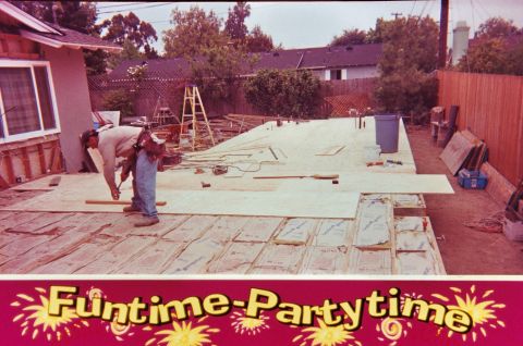 1989 Ford F-250 - A construction worker is busy on a deck project, with building materials and tools scattered around the site.