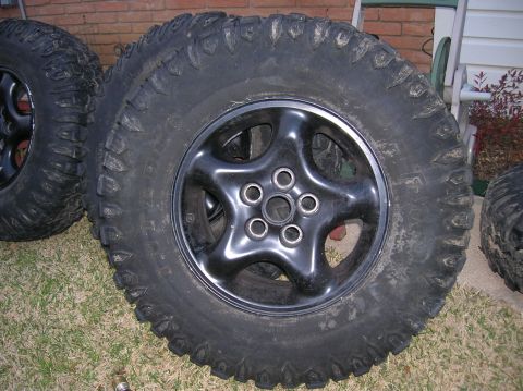 1999 Land Rover Discovery II - Several off-road tires with aggressive tread patterns are shown mounted on black five-spoke wheels.