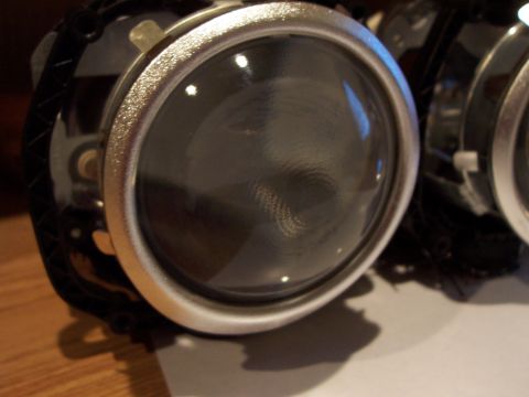 1993 Ford Probe - A car headlight projector assembly is shown in detail, focusing on its lens and bezel.