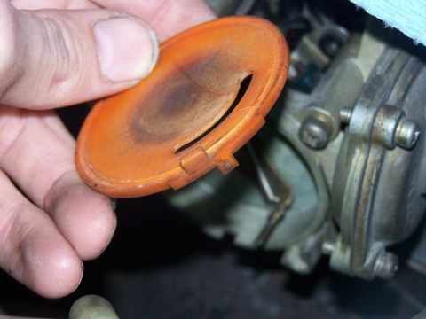 1986 Ford Bronco - A hand holds an orange carburetor choke cover, revealing internal engine components.