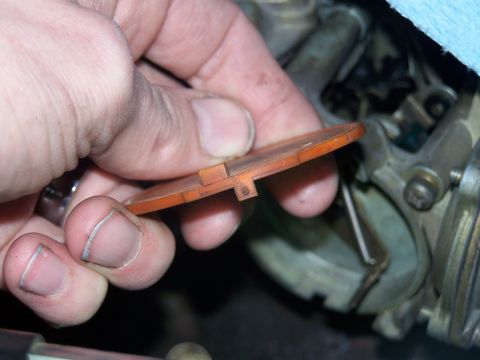 1986 Ford Bronco - Close-up of a hand holding a carburetor choke plate, with the carburetor visible in the background.
