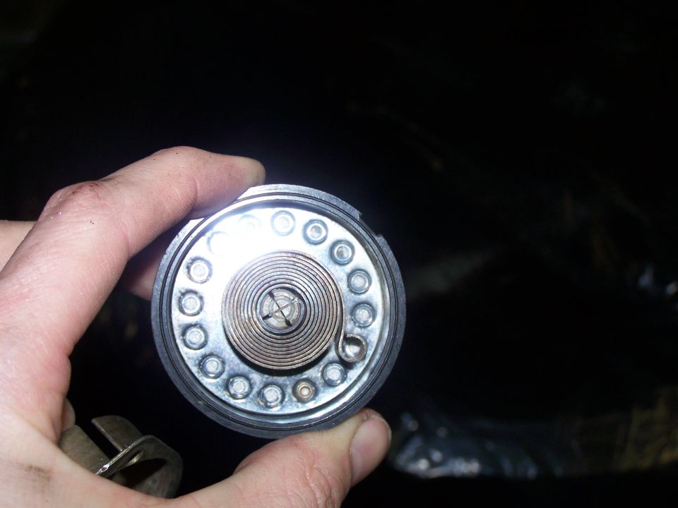 Choke mechanism with coiled spring and screw, held by hand