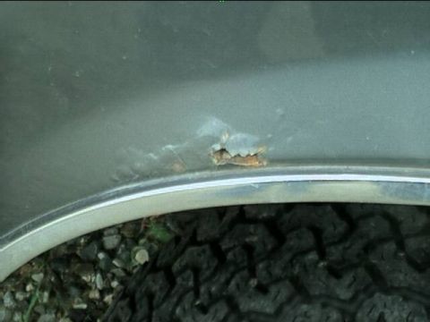 1989 Ford Bronco - Close-up of rust damage on the fender flare of a vehicle.