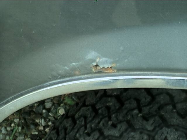 Rust hole on fender flare above tire