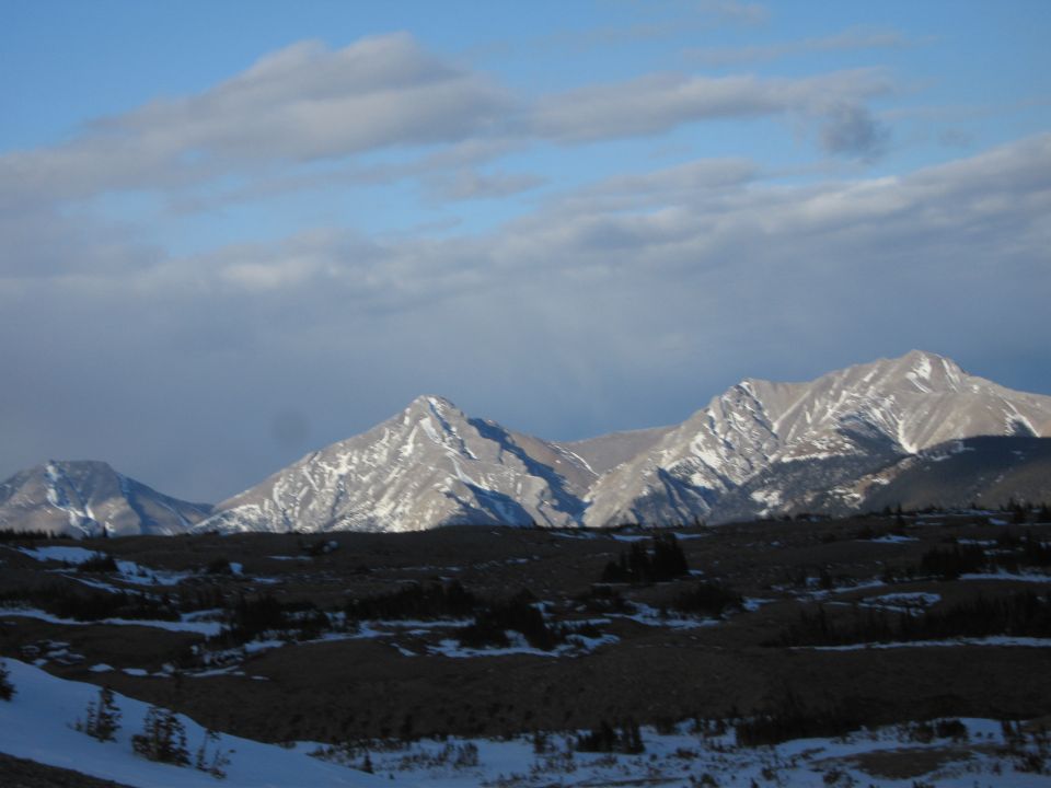 Snow-covered mountain range under a partly cloudy sky in winter