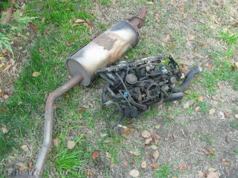 1987 Suzuki Samurai - Engine and exhaust system components are visible on the ground.