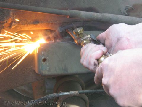 1987 Suzuki Samurai - Metal frame being cut with a torch, generating a shower of sparks.