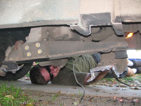 1987 Suzuki Samurai - A person works on the undercarriage of a vehicle, performing welding repairs.