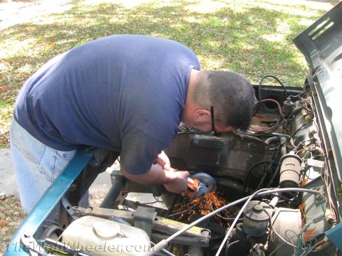 1987 Suzuki Samurai - A man uses an angle grinder in the engine bay of a 1987 Suzuki Samurai, creating a shower of sparks.