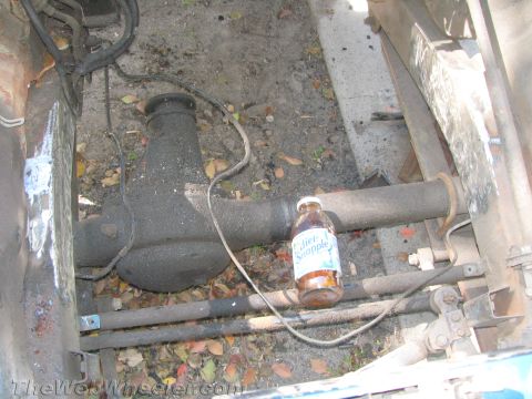 1987 Suzuki Samurai - Close-up of a vehicle's rear differential and suspension parts, with a drink bottle for scale.