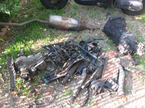 1987 Suzuki Samurai - Disassembled vehicle components are laid out on the grass, awaiting reassembly or disposal.