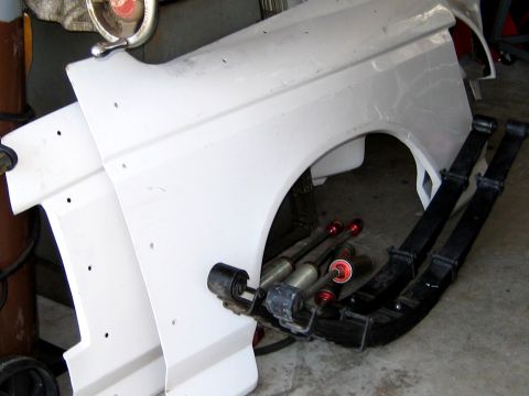1996 Ford Bronco - Vehicle fender and suspension components are laid out on the floor.