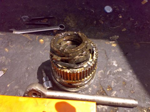 1995 Ford F-150 - A close-up view of a heavily greased and worn wheel bearing assembly, surrounded by tools.