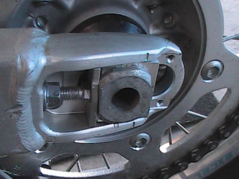 2007 Yamaha YZ450F - This image shows a close-up view of the rear axle adjustment mechanism on a motorcycle, including the bolt and part of the chain.