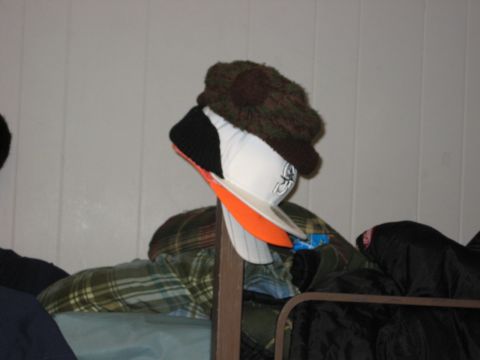 1980 Ford Bronco - Hats and winter clothes are stacked on a rack against a white wall.