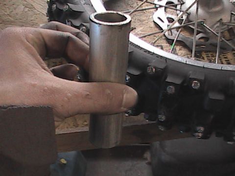 2007 Yamaha YZ450F - A hand holds a metal tube near the knobby tire and spokes of a motorcycle wheel.