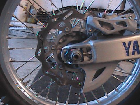 2007 Yamaha YZ450F - Rear wheel assembly of a motorcycle, showing the brake rotor and swingarm with Yamaha branding.