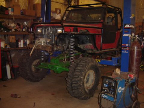 1992 Ford Bronco - Custom off-road vehicle undergoing modifications in a workshop, with welding equipment nearby.